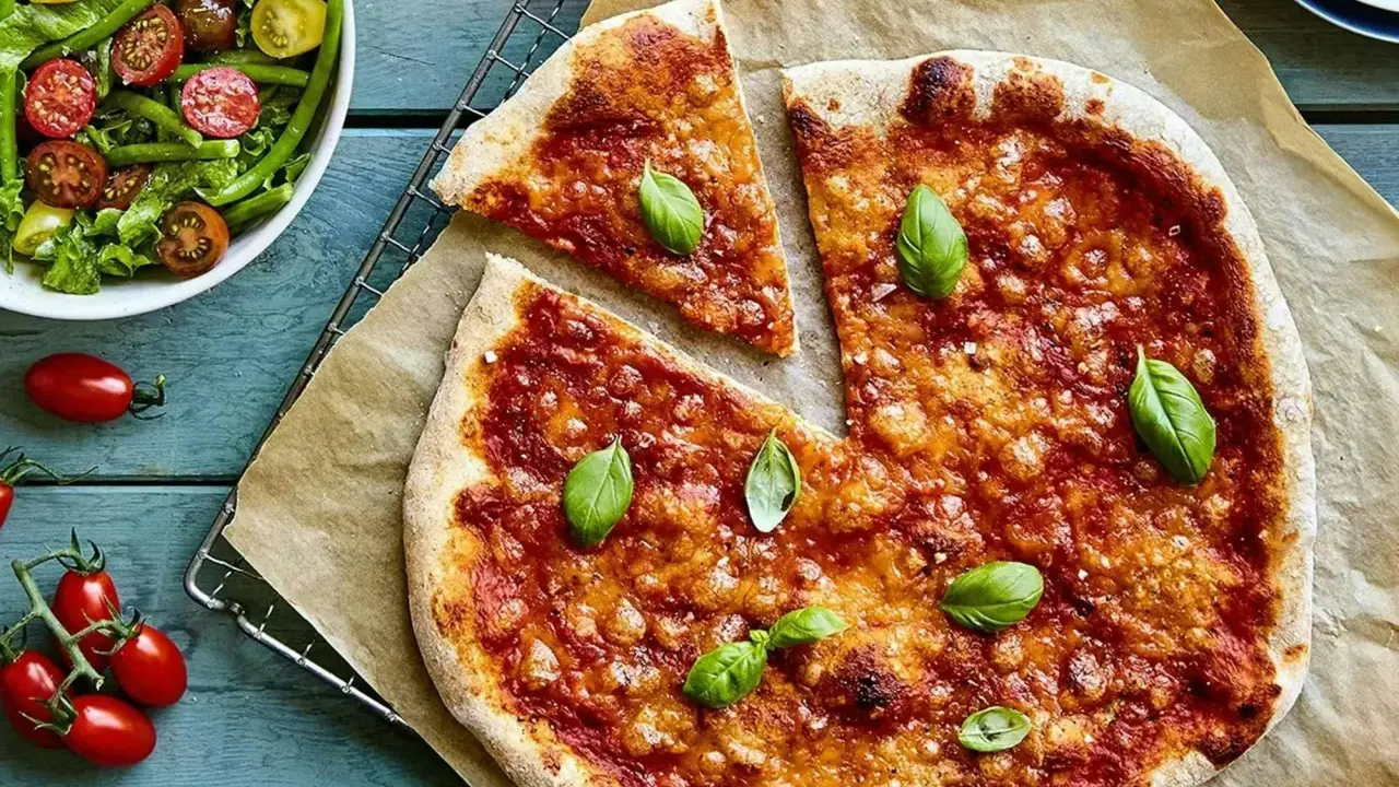 En härlig, nyttig pizza med tomatsås och ost, toppad med färsk basilika. Bredvid en fräsch sallad med gröna bönor och tomater.