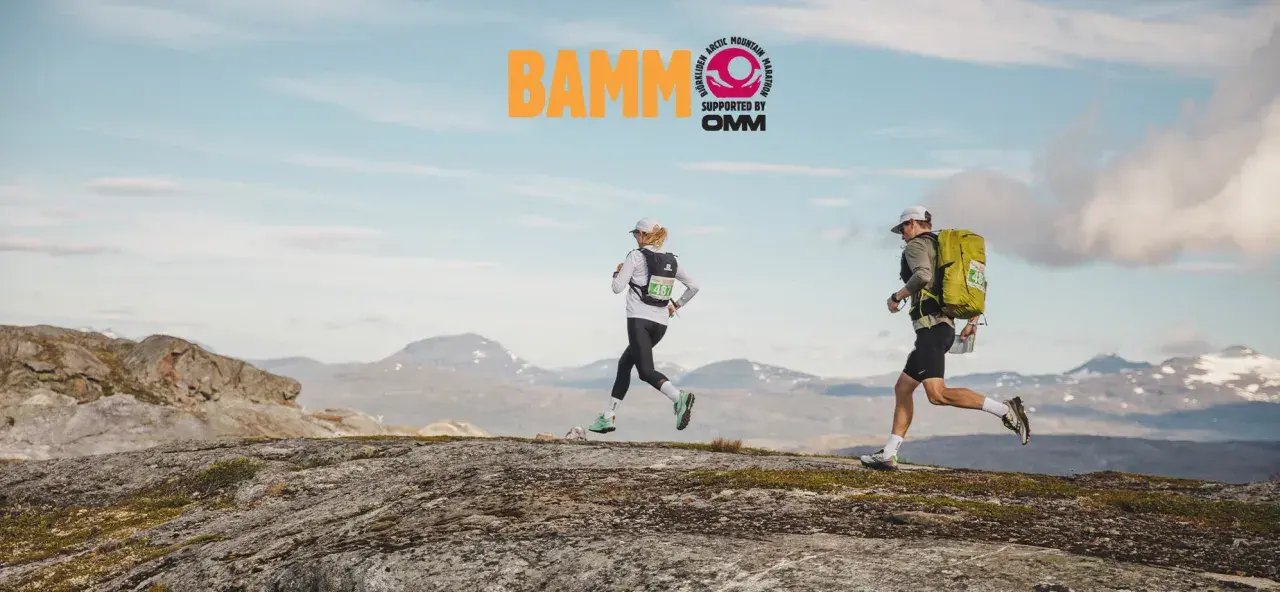 Två löpare springer över kargt fjällandskap. BAMM-loggan syns högt upp.