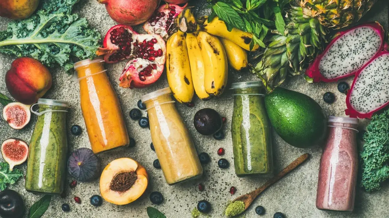 Färgglada smoothies i flaskor, omgivna av färsk frukt och grönsaker. En visuell påminnelse om vad betyder detox för kroppen.