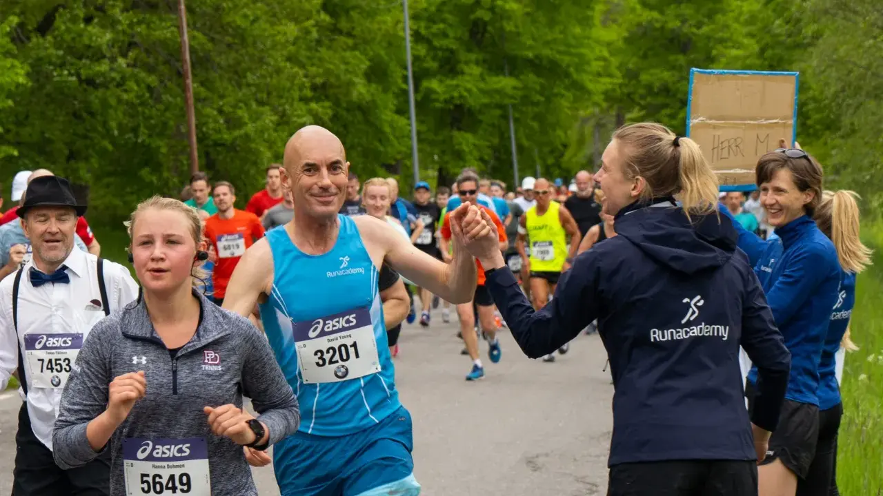 Glada löpare hejar på varandra under sista veckan innan halvmarathon. En man ger en high five till en kvinna.
