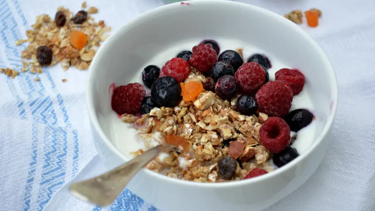 En skål med yoghurt, fil och flingor toppad med färska hallon, blåbär och torkad frukt. En perfekt start på dagen!