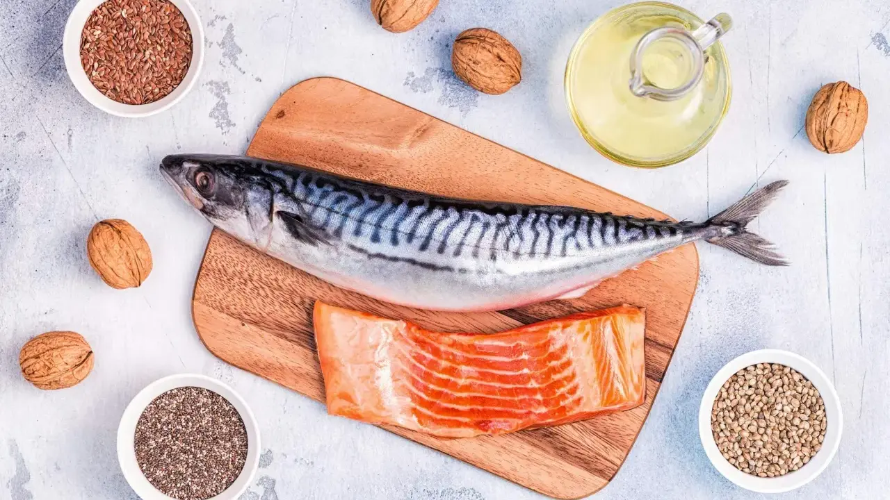 Makrill, laxfilé, valnötter och frön som linfrön, chiafrön och hampafrön. En flaska med olja, kanske rapsolja omega 3, står bredvid.