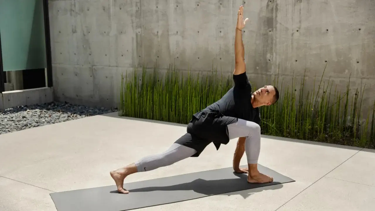 Man i yoga-ställning, med en arm sträckt uppåt. Han springer fort i sin träning.