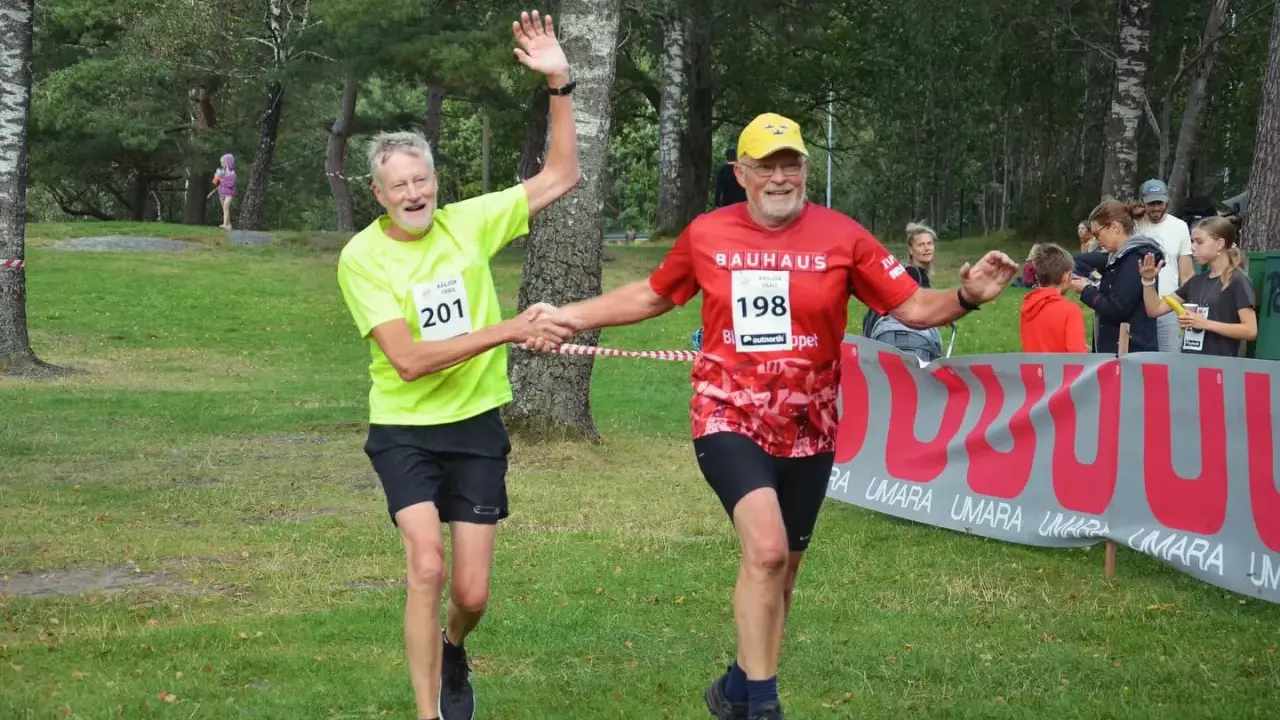 Två glada löpare, nummer 201 och 198, skakar hand vid målgången på kåsjön trail.