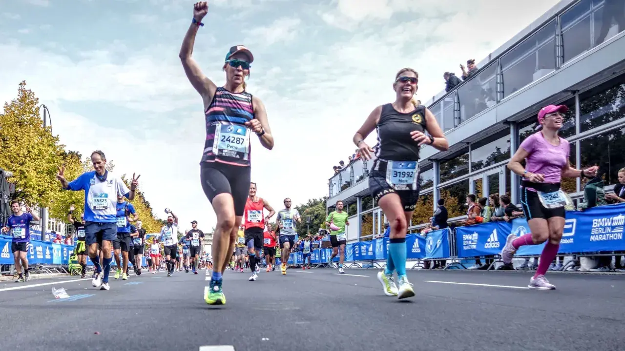 Glada löpare i BMW Berlin Marathon. Petra, med nummer 24287, firar sin framgång. En härlig dag för runners world triathlon.