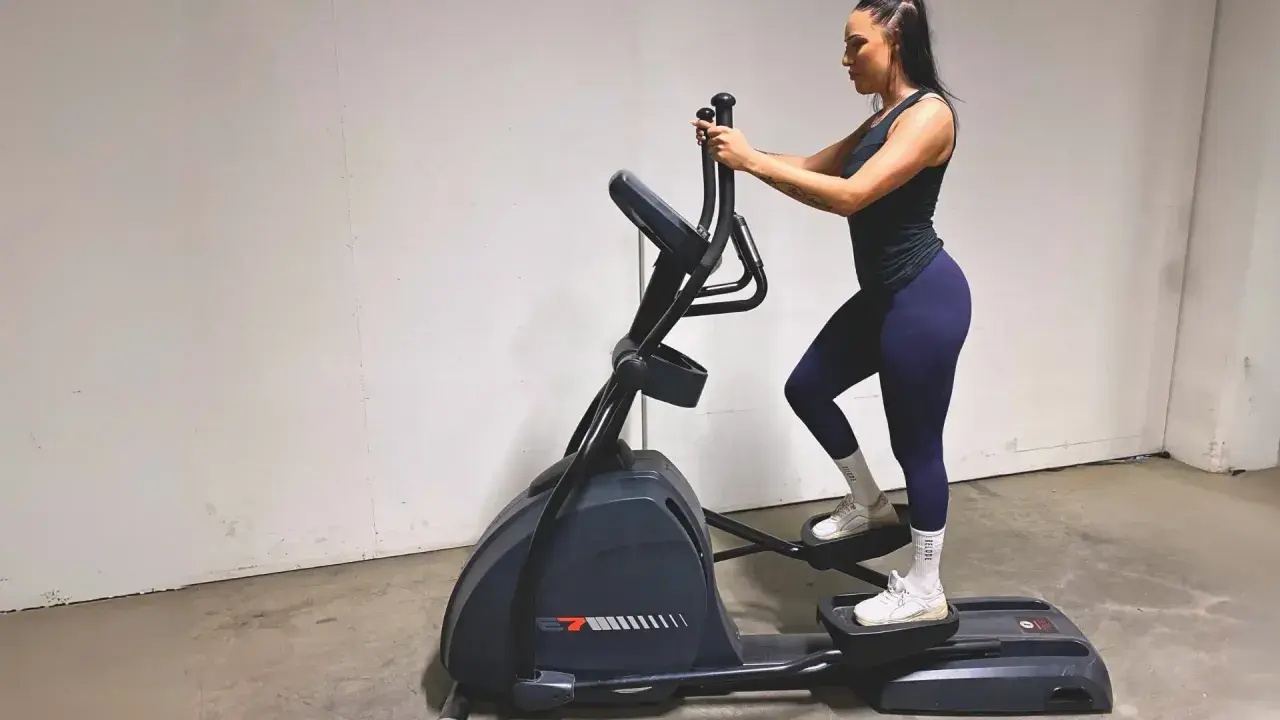 Kvinna tränar på crosstrainer och bygger upp sina muskler.