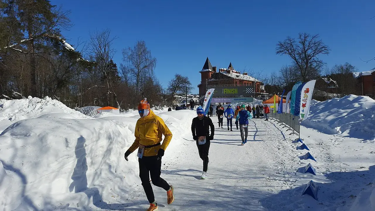 Löpare i snöig terräng, på väg mot en finishlinje. Kanske ett backyard ultra rekord sätts idag!