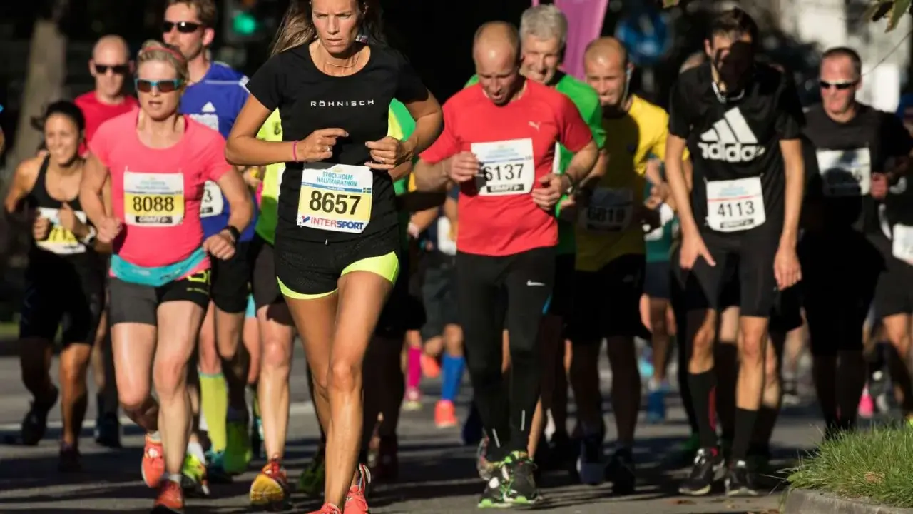 Löpare i Stockholm Halvmarathon kämpar för ett rekord. En kvinna med nummer 8657 leder loppet.