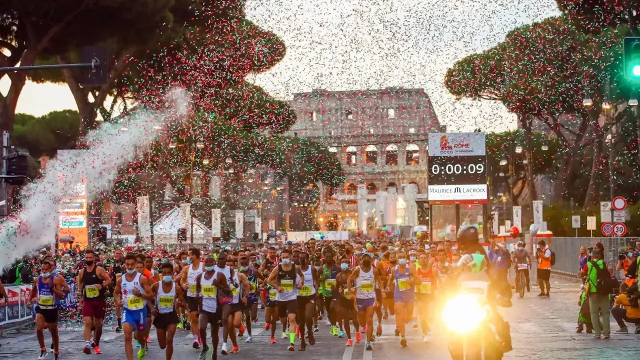 Löpare i Rom-maraton passerar Colosseum under konfettiregn.