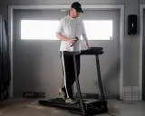 Man med keps tränar på löpband, siktar på att springa 5 km på 30 min.