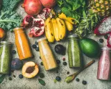 Färgglada smoothies i flaskor, omgivna av färsk frukt och grönsaker. En visuell påminnelse om vad betyder detox för kroppen.