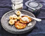 En tallrik med pannkakor toppade med keso och bananskivor. Perfekt för ett proteinrikt keso mellanmål.
