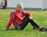 En löpare i röd jacka och svarta tights vilar i gräset, redo att springa milen under 50 minuter.
