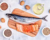 Makrill, laxfilé, valnötter och frön som linfrön, chiafrön och hampafrön. En flaska med olja, kanske rapsolja omega 3, står bredvid.