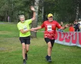 Två glada löpare, nummer 201 och 198, skakar hand vid målgången på kåsjön trail.