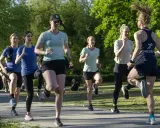 Grupp kvinnor tränar löpning i parken, ett intensivt backintervaller pass.
