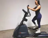 Kvinna tränar på crosstrainer och bygger upp sina muskler.
