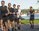 En grupp män springer längs en strandpromenad. De verkar njuta av sin aktiva vila i solen.