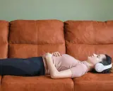 En elitidrottare vilar på en soffa med hörlurar, fokuserad på sin vilopuls.
