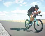 Cyklist i full fart på en landsväg, redo för olympisk distans triathlon.