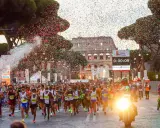 Löpare i Rom-maraton passerar Colosseum under konfettiregn.