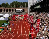 Löpare korsar mållinjen på stockholm marathon bana. Publiken jublar från läktaren.