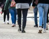 En grupp människor går på en trottoar. De har på sig jeans och sneakers. Kanske är de på väg att nå sina 10000 steg kcal.