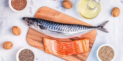 Makrill, laxfilé, valnötter och frön som linfrön, chiafrön och hampafrön. En flaska med olja, kanske rapsolja omega 3, står bredvid.