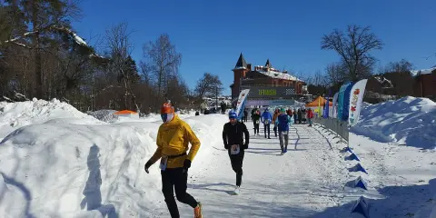 Löpare i snöig terräng, på väg mot en finishlinje. Kanske ett backyard ultra rekord sätts idag!