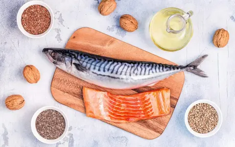 Makrill, laxfilé, valnötter och frön som linfrön, chiafrön och hampafrön. En flaska med olja, kanske rapsolja omega 3, står bredvid.