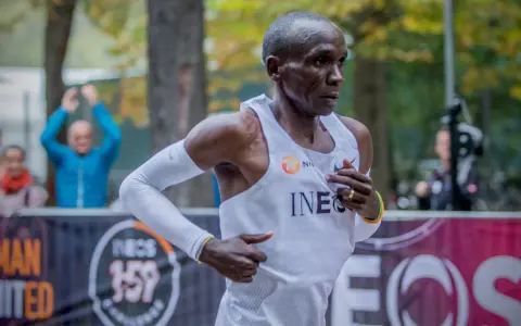 Eliud Kipchoge springer mot sitt mål, det snabbaste maraton någonsin. Publiken hejar på i bakgrunden.