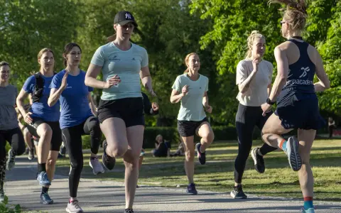 En grupp kvinnor tränar löpning i en park, redo att springa 3 km.