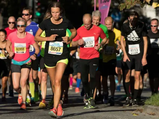 Kvinnlig löpare med nummer 8657 i Stockholm halvmaraton. Hon fokuserar på sitt halvmaraton tid.