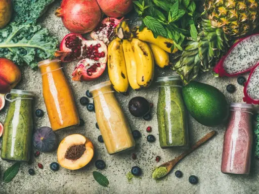 Färgglada smoothies i flaskor, omgivna av färsk frukt och grönsaker. En visuell påminnelse om vad betyder detox för kroppen.
