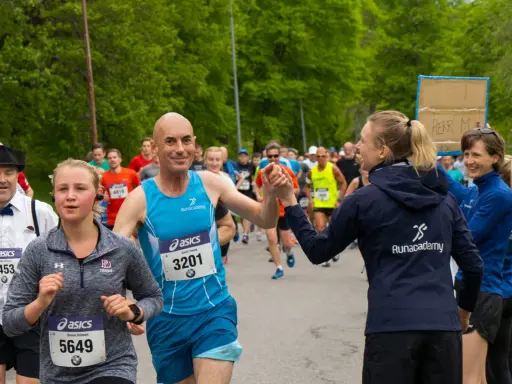 Glada löpare hejar på varandra under sista veckan innan halvmarathon. En man ger en high five till en kvinna.