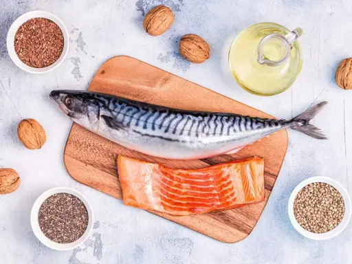 Makrill, laxfilé, valnötter och frön som linfrön, chiafrön och hampafrön. En flaska med olja, kanske rapsolja omega 3, står bredvid.
