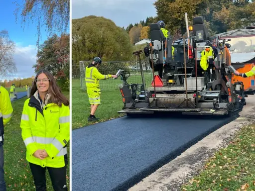 Två personer i varselkläder står framför en asfaltsläggare som lägger nytt asfalt.