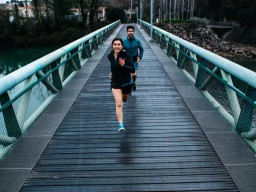 Ett par springer över en bro, redo för sitt 10 km lopp.