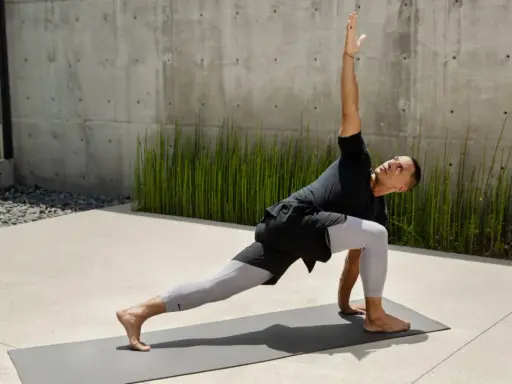 Man i yoga-ställning, med en arm sträckt uppåt. Han springer fort i sin träning.