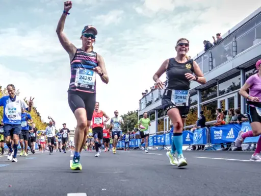 Glada löpare i BMW Berlin Marathon. Petra, med nummer 24287, firar sin framgång. En härlig dag för runners world triathlon.