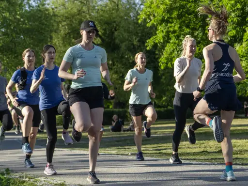 En grupp kvinnor tränar löpning i en park, redo att springa 3 km.