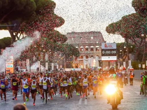 Löpare i Rom-maraton passerar Colosseum under konfettiregn.