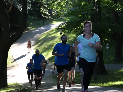 En grupp löpare i en park, en kvinna i ljusblå tröja springer framåt. Kanske undrar du vad betyder anaerob träning när du ser dem kämpa uppför backen.