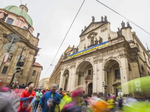 Löpare i Prag halvmarathon passerar en byggnad med en banderoll "HANDS OFF UKRAINE, PUTIN!".