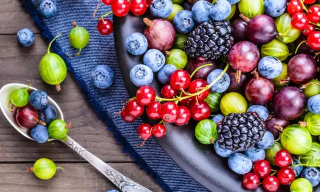 En sked fylld med blåbär, krusbär och vinbär. En härlig blandning av socker i frukt, redo att avnjutas.