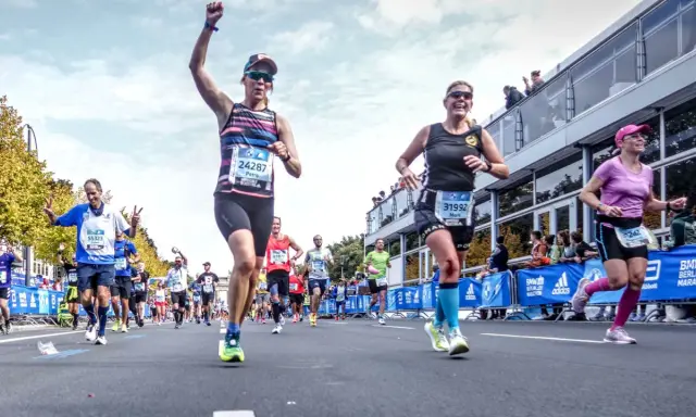 Glada löpare i BMW Berlin Marathon. Petra, med nummer 24287, firar sin framgång. En härlig dag för runners world triathlon.