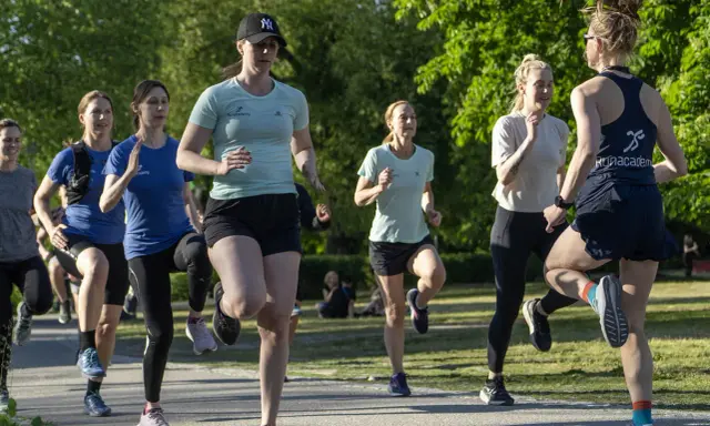 En grupp kvinnor tränar löpning i en park, redo att springa 3 km.