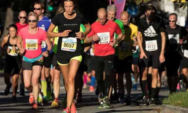 Löpare i Stockholm Halvmarathon kämpar för ett rekord. En kvinna med nummer 8657 leder loppet.