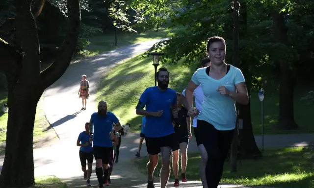 En grupp löpare i en park, en kvinna i ljusblå tröja springer framåt. Kanske undrar du vad betyder anaerob träning när du ser dem kämpa uppför backen.