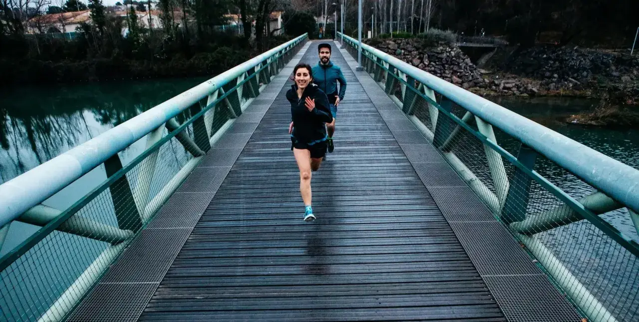 Ett par springer över en bro, redo för sitt 10 km lopp.
